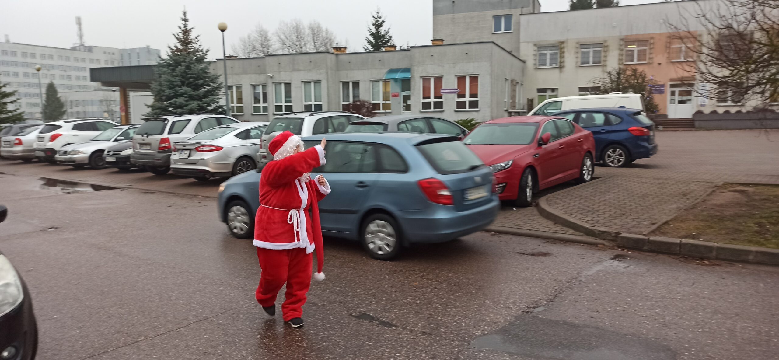 Mikołaj w Mikołajki macha ręką do przejeżdzających aut