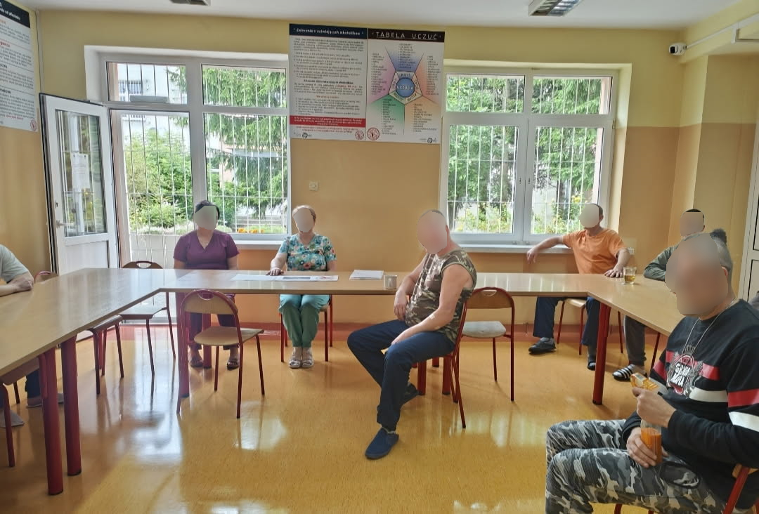 Zajęcia na sali. Kilku mężczyzn słucha jak kobieta opowiada