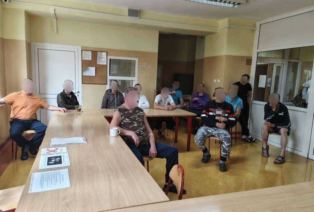 Zajęcia na sali. Kilku mężczyzn słucha jak kobieta opowiada
