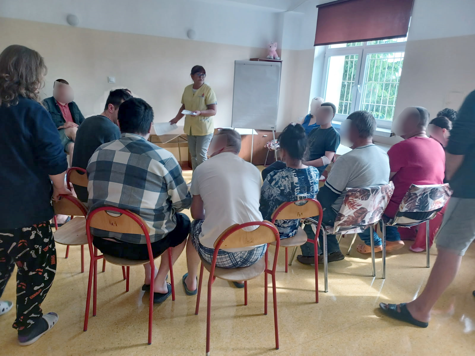 Grupa ludzi siedzi w salce na zajęciach jest widno Słuchają wykładu