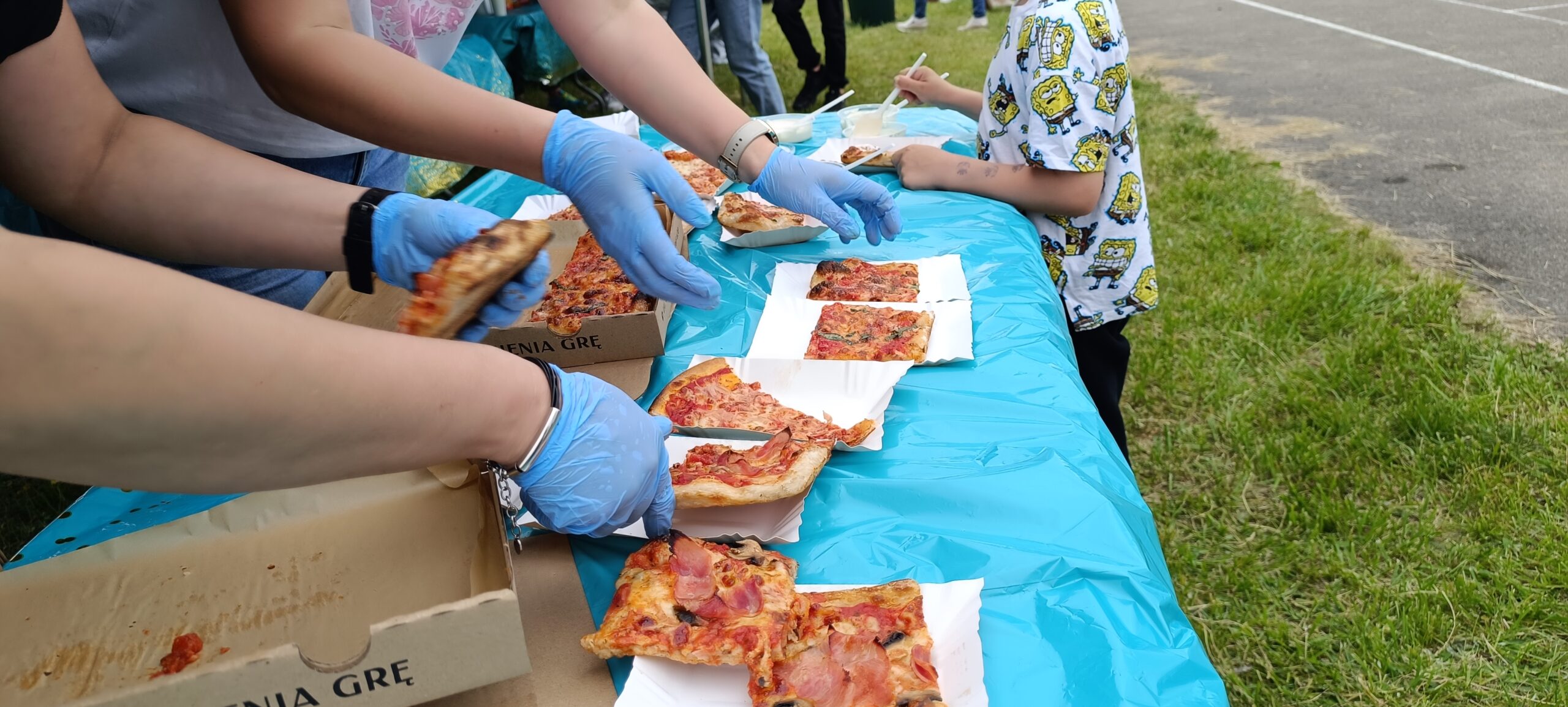 Panie Rozdają pizzę dzieciom na podwórku podczas festynu