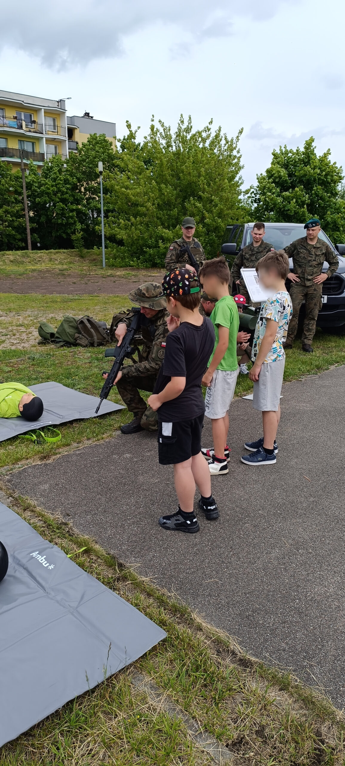 Grupa chłopców ogląda pokazywany karabin przez żołnierza