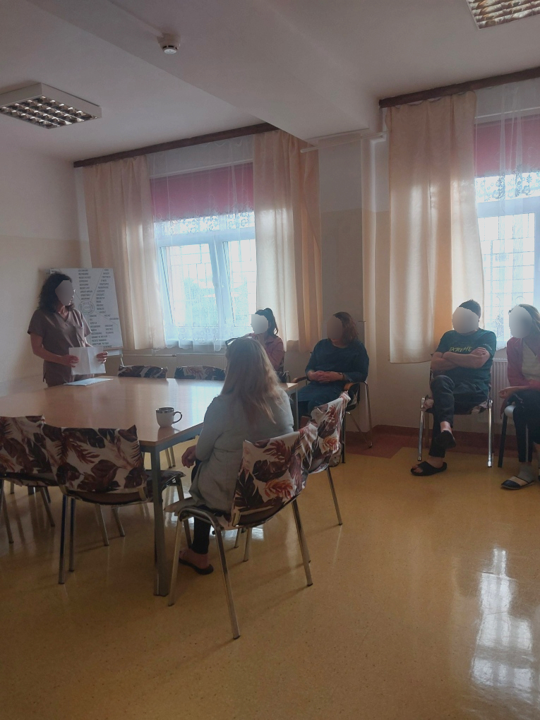 Zajęcia na sali. Kilku mężczyzn słucha jak kobieta opowiada