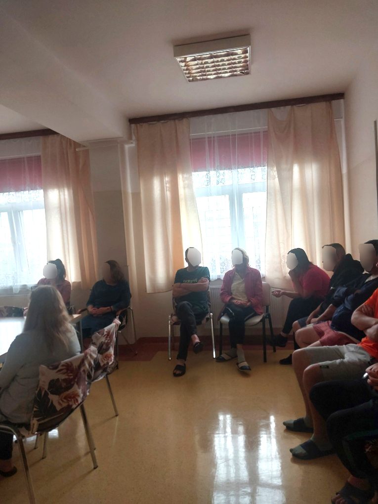 Zajęcia na sali. Kilku mężczyzn słucha jak kobieta opowiada