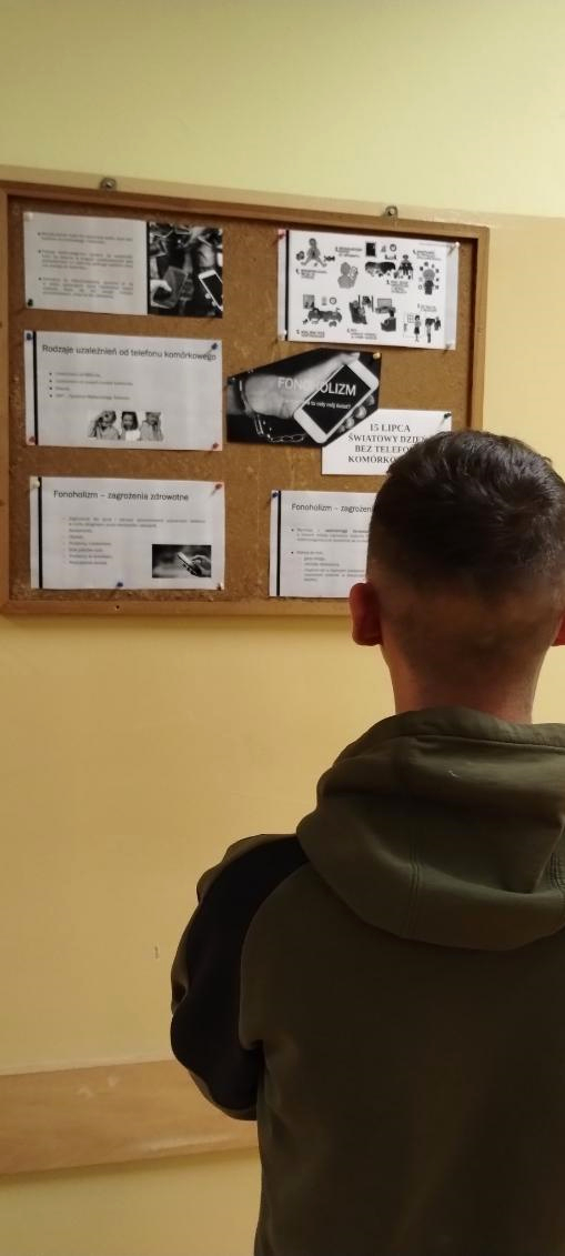 Mężczyzna spogląda na na gazetkę na tablicy korkowej. Czyta jakieś informacje