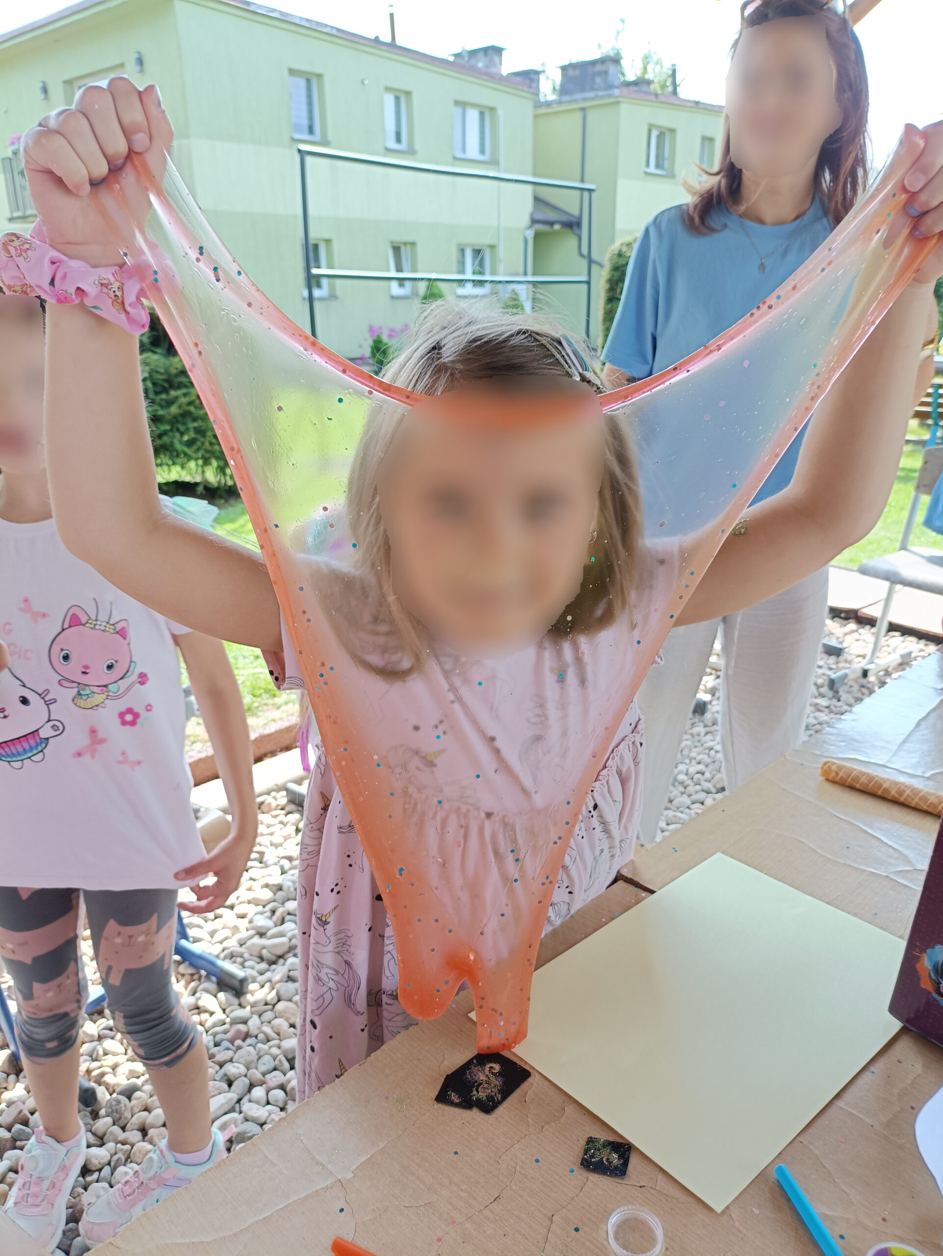 Zabawa na podwórku, dziewczynaka trzyma rozłozony slime