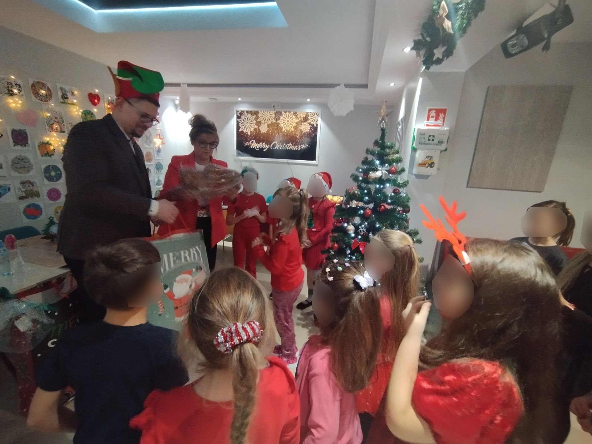 Impreza Mikołajkowa na sali pełnej dzieci, choinka rozdawanie prezentów, warsztaty
