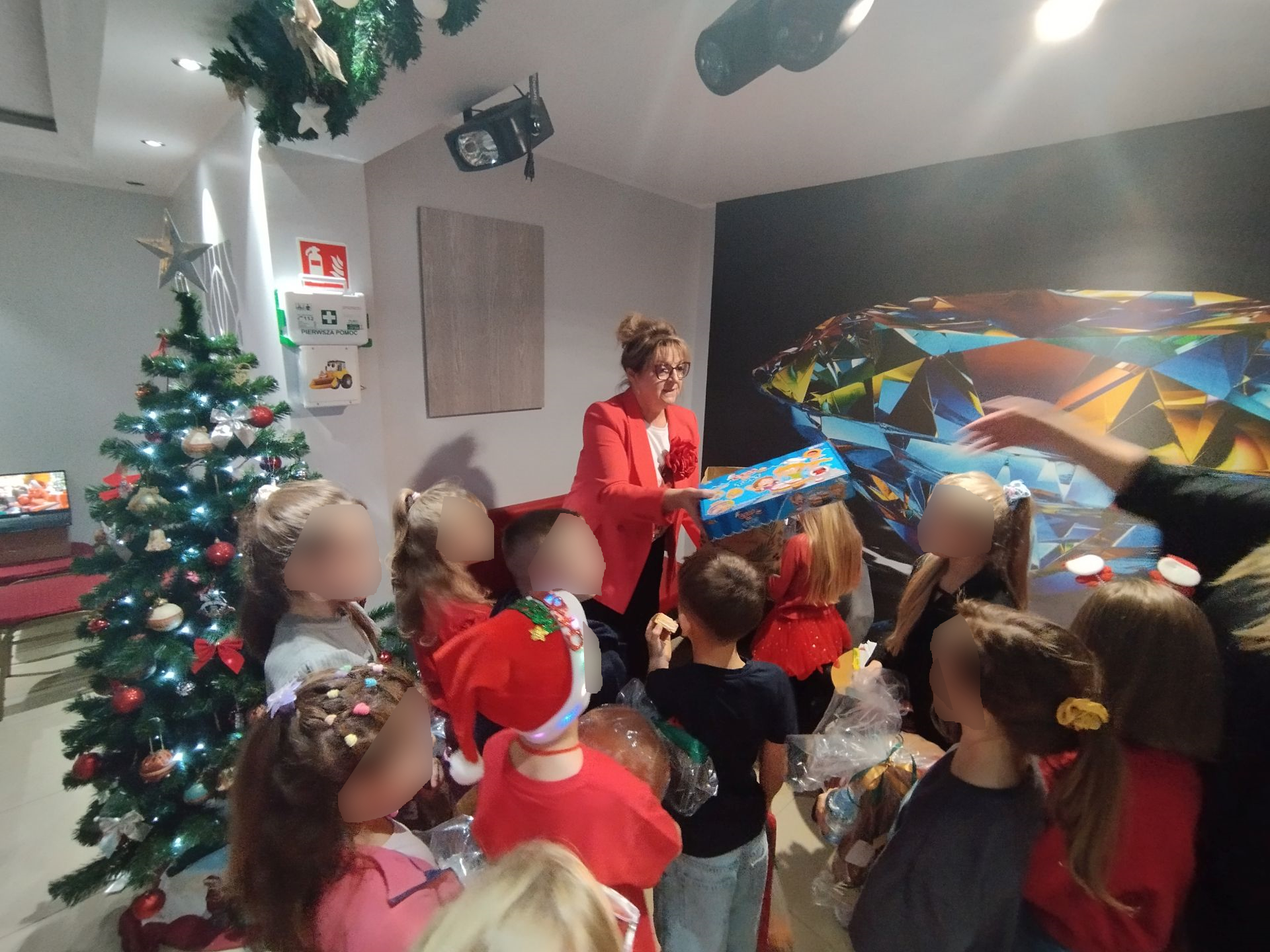 Impreza Mikołajkowa na sali pełnej dzieci, choinka rozdawanie prezentów, warsztaty