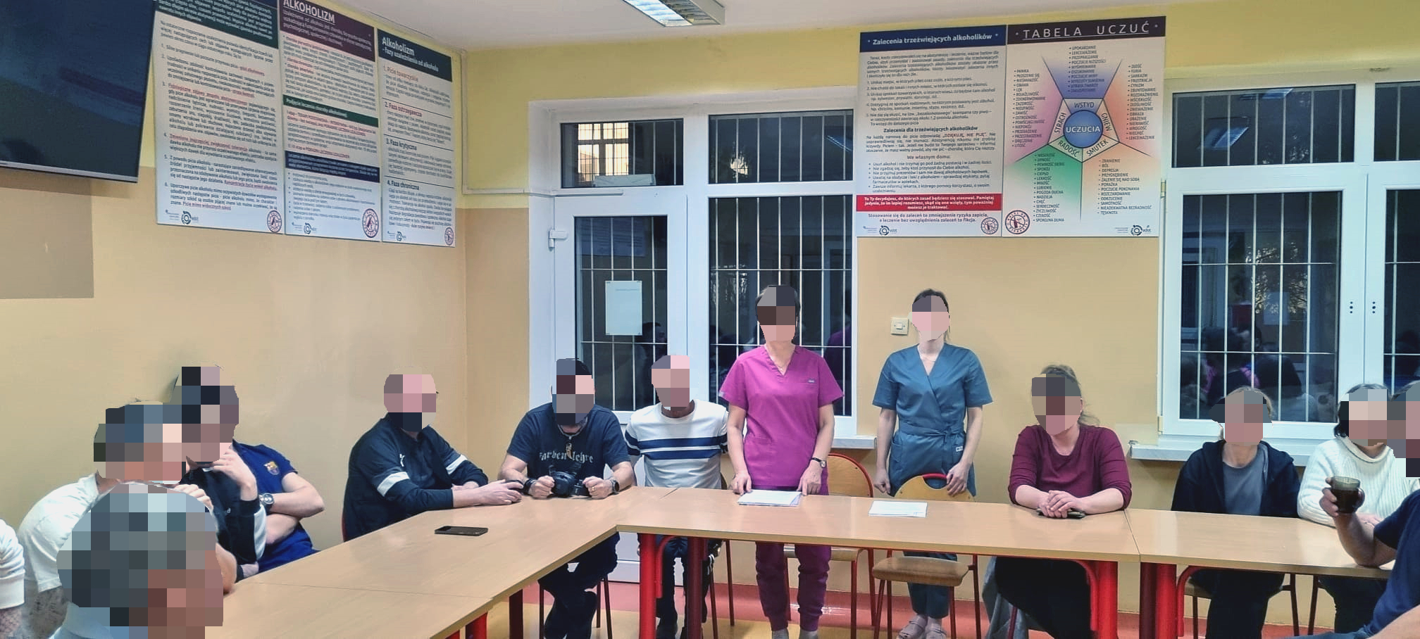 Grupa ludzi słucha wykładu na stołówce, za oknem wyraźny wieczór