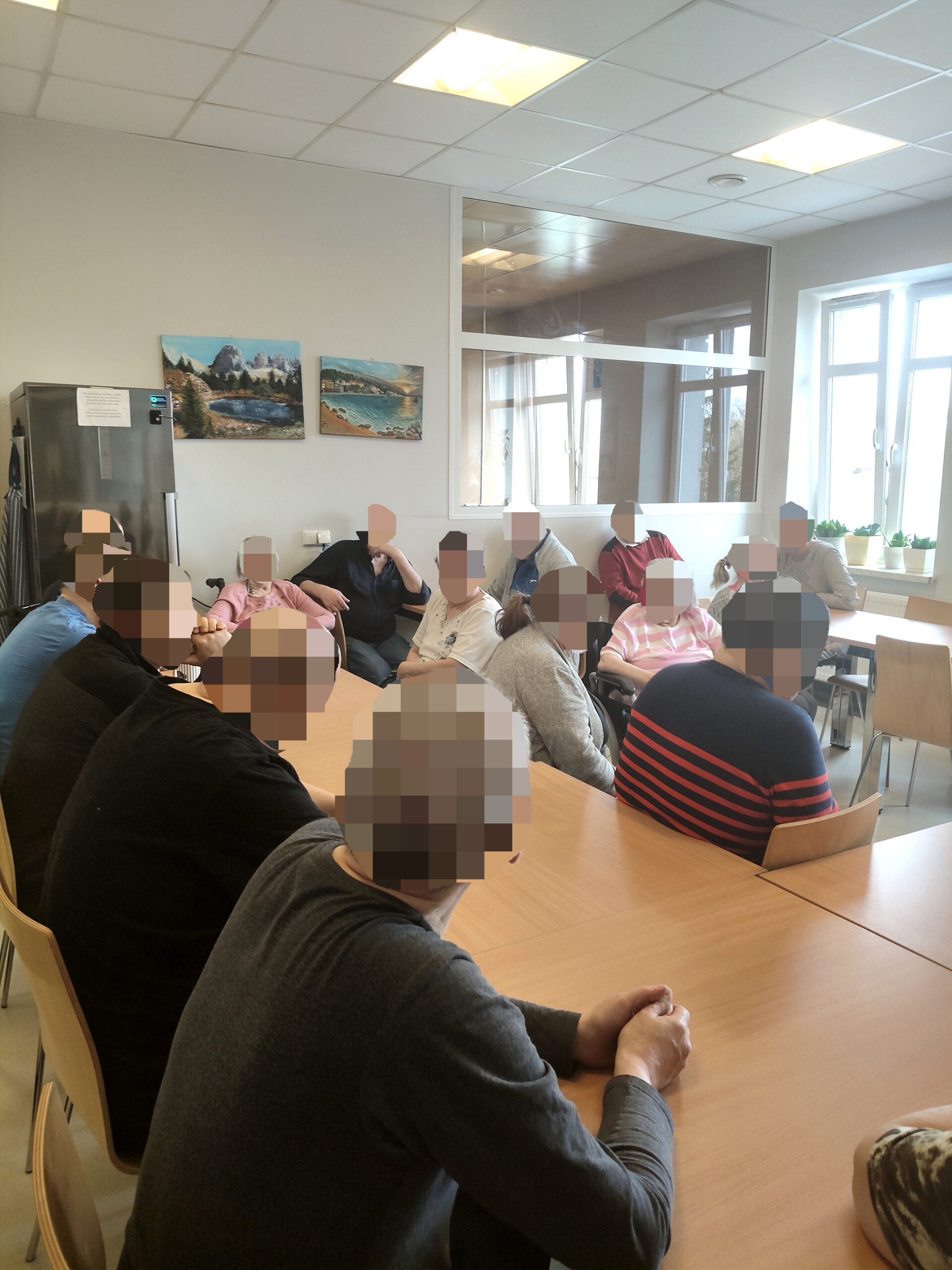 Sala konferencyjna, gruba mężczyzn siedzi i słucha wykładu.