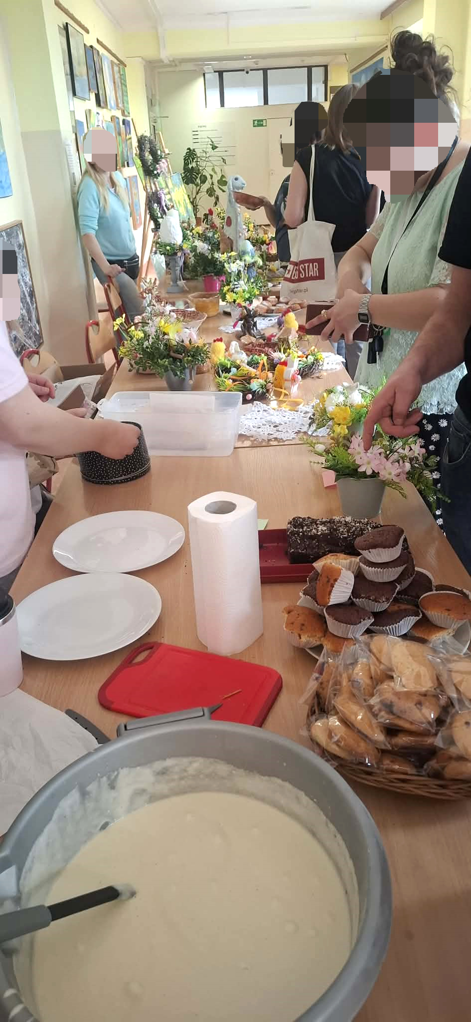 sala szpitalna wystawa prac wielkanocnych , dużo ludzi, na stołach rozstawione świątecznestroiki, , młodzież robi gofry