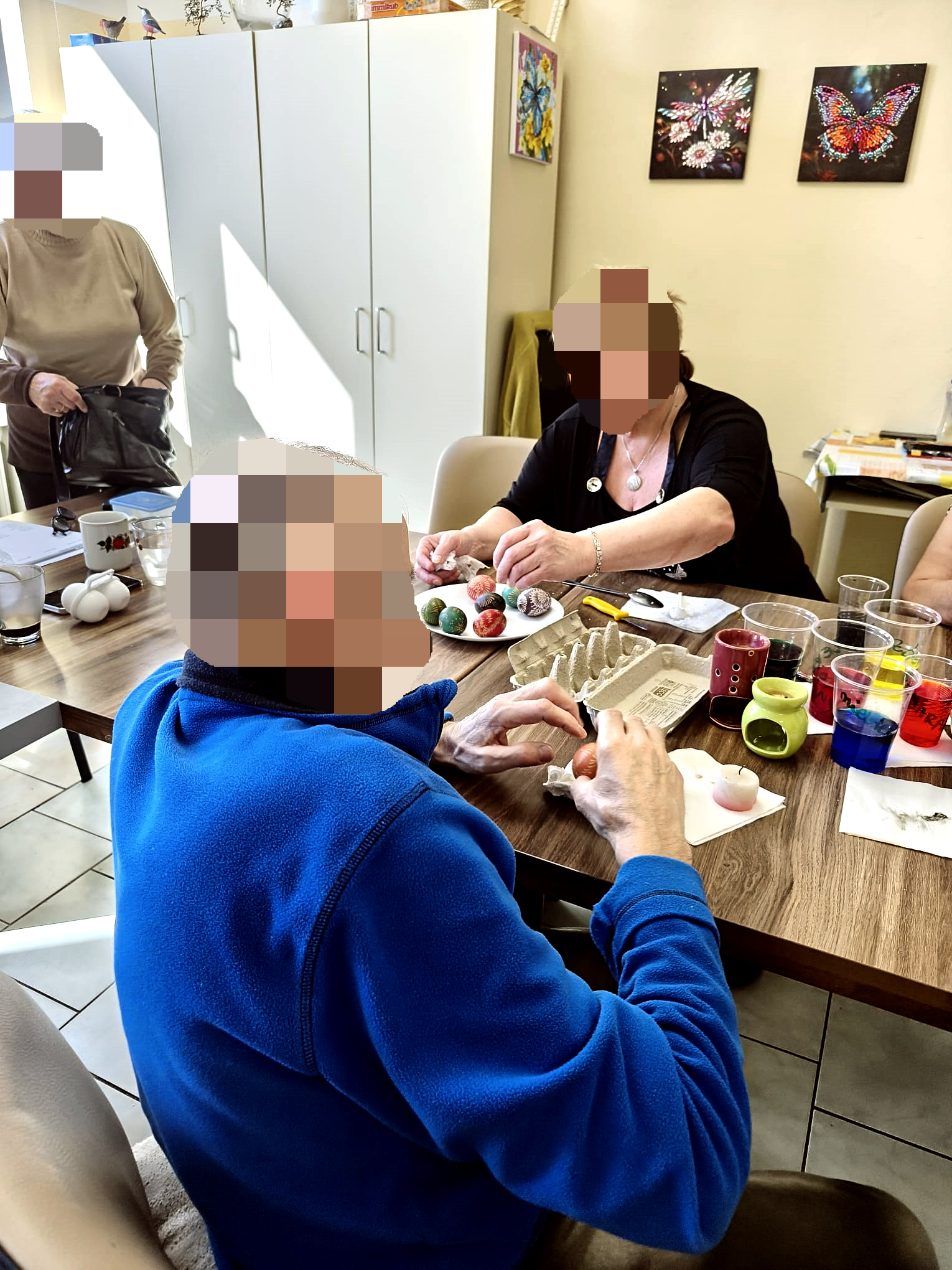 Warsztaty malowania jajek świątecznych. Kobieta oraz mężczyzna na stoliku wykonuje malowanie jajka tradycyjną metodą