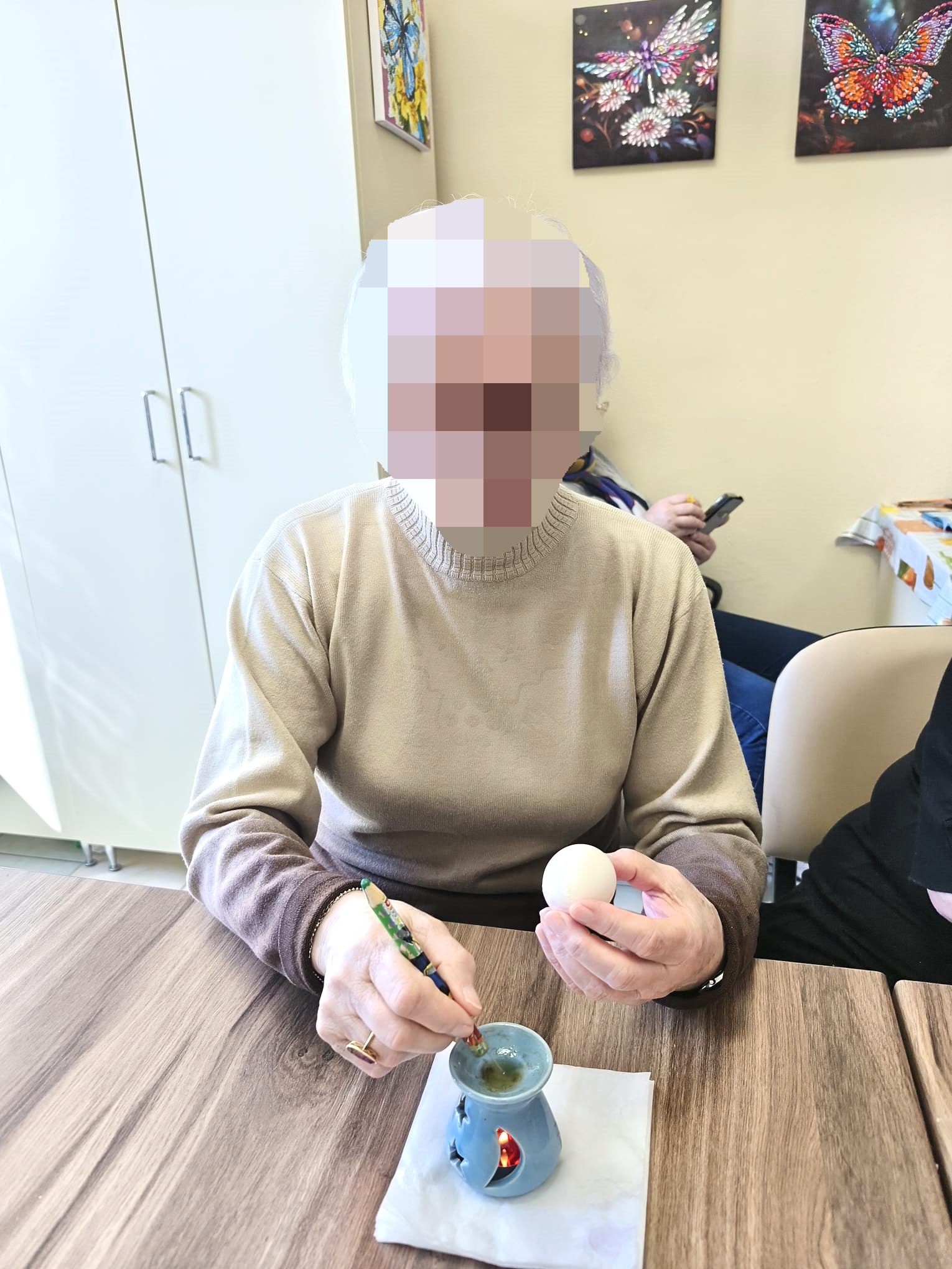 Warsztaty malowania jajek świątecznych. Kobieta na stoliku wykonuje malowanie jajka tradycyjną metodą