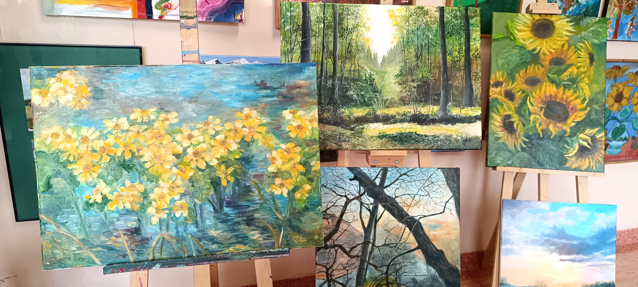 sala szpitalna wystawa prac wielkanocnych , . Stoją piekne obrazy malowane farbami, tematycha wiosenno świateczna. Obrazy umieszczone są na sztalugach