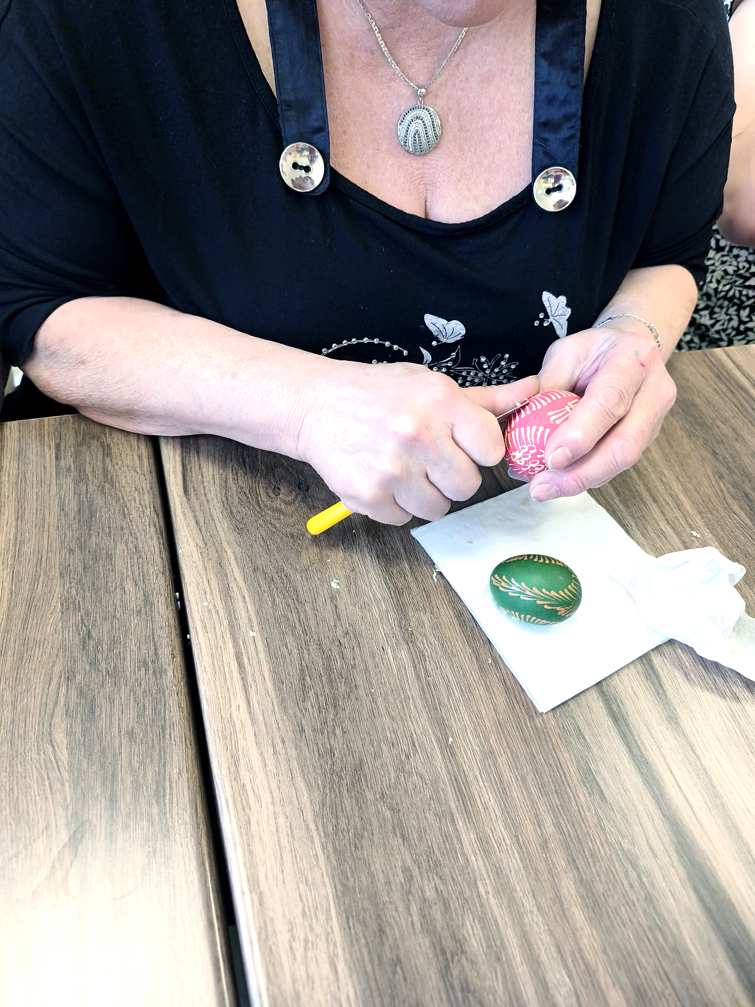 Warsztaty malowania jajek świątecznych. Kobieta na stoliku wykonuje malowanie jajka tradycyjną metodą