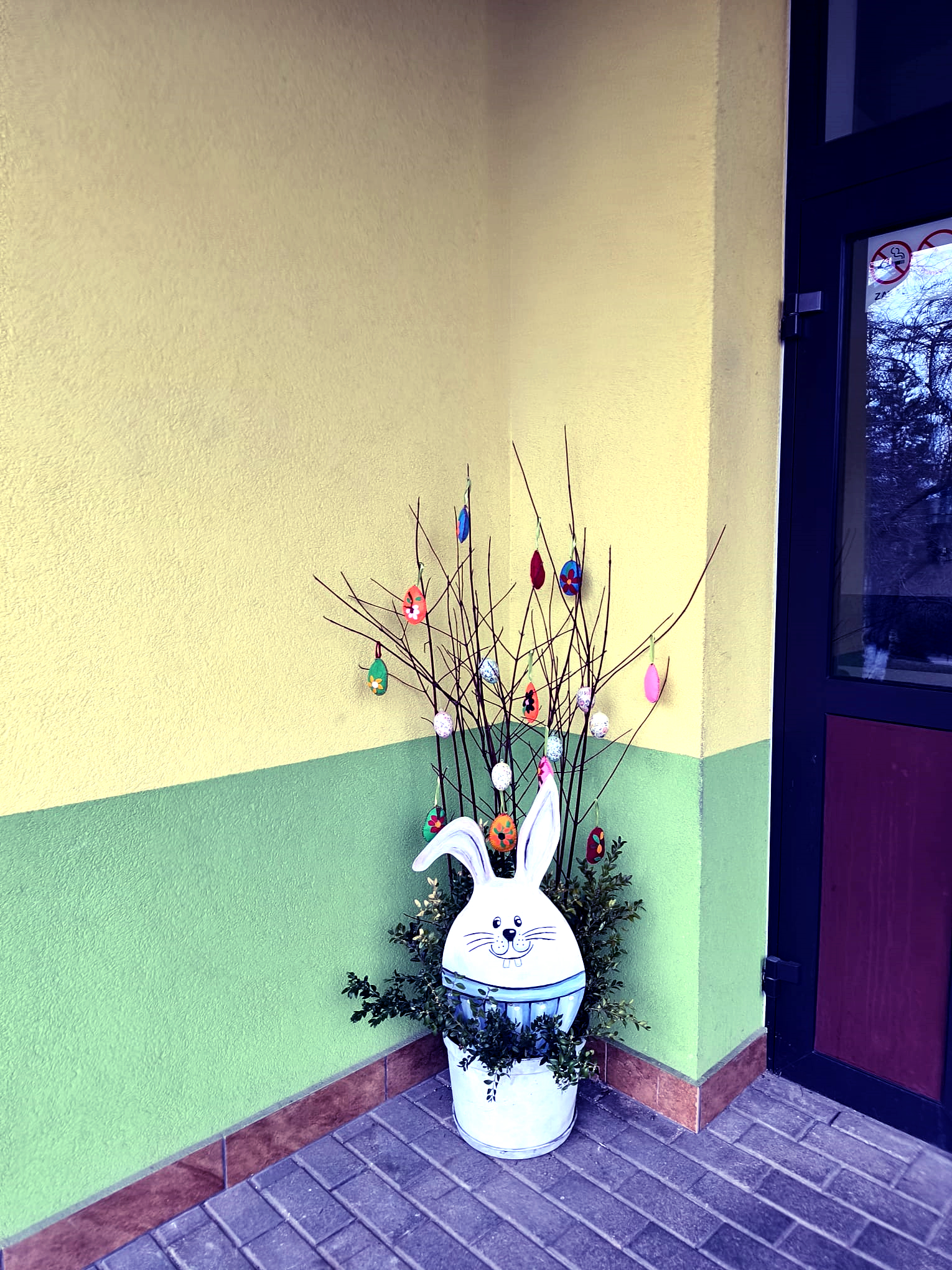 Wejście do obiektu , przed wejsciem stroik w lewym kącie w postaci zajączka wielkanocnego. Z zajączka wystają gałązki przyzdobione jajeczkami