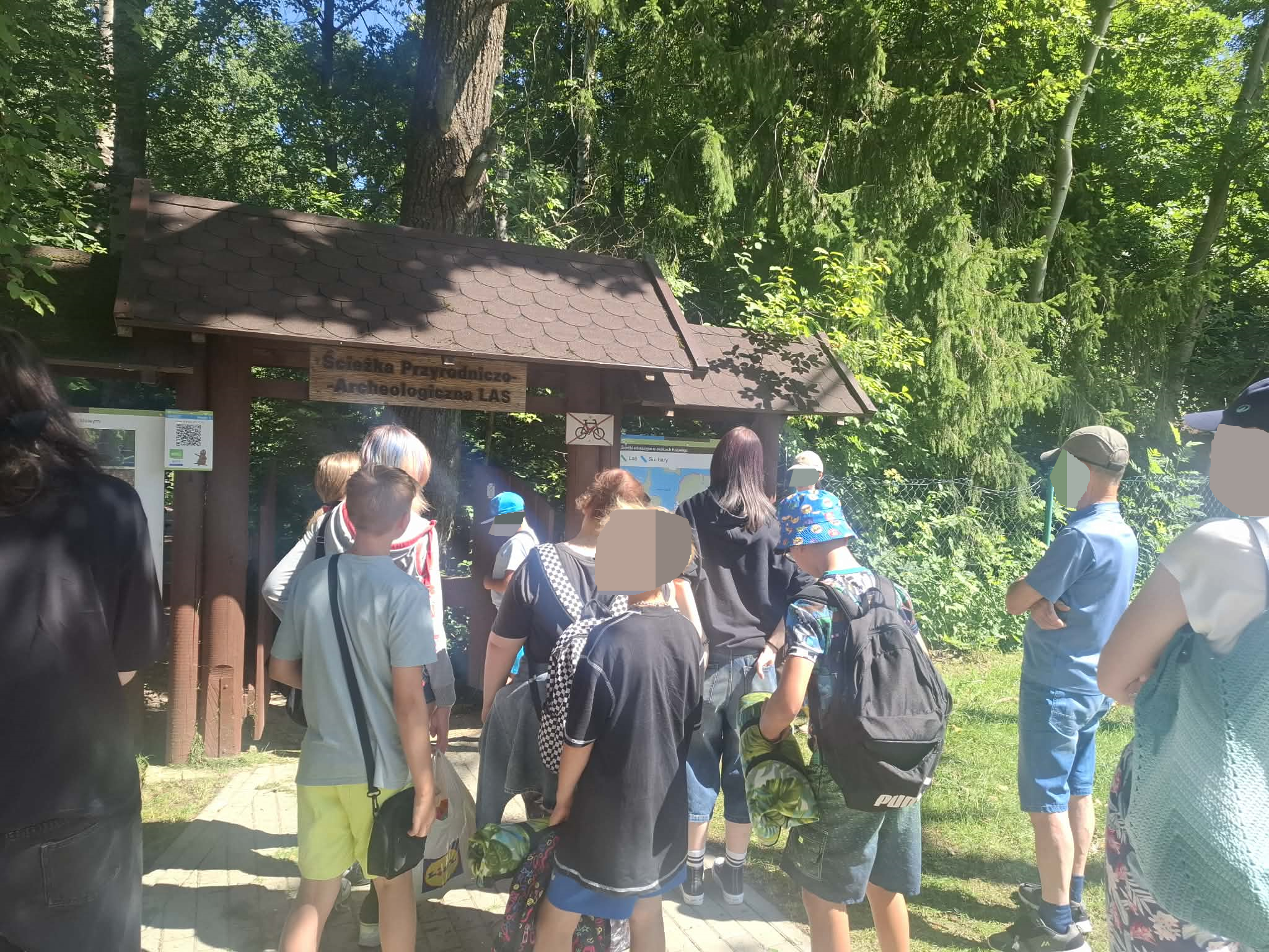 Młodzież w lesie na wycieczce słucha przewodnika